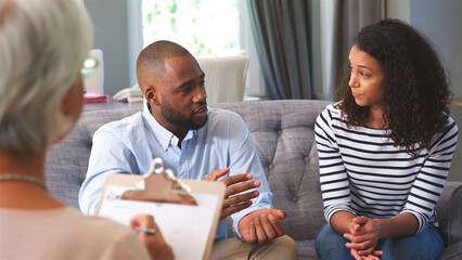 Couple At Home Meeting With Financial Advisor To Discuss Investments Pension And Savings