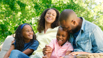 Smiling Family Sitting On Outdoor Seat In Summer Garden Together