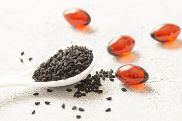 Pills of black cumin seeds essential oil on rustic background. Nigella Sativa capsules, healthy food supplement