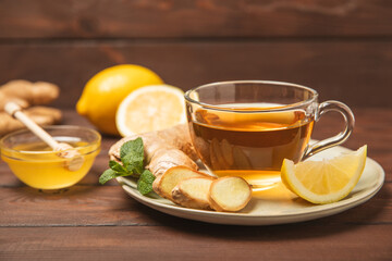 Cup of hot ginger tea with slices of ginger root on wooden background. Warming drink. Alternative medicine. Tea with honey, lemon, ginger and mint. Space for text. Copy space