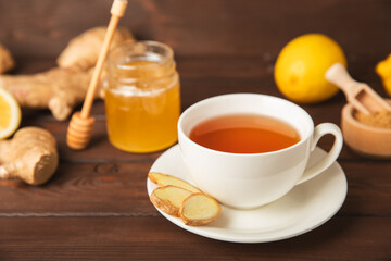 Cup of hot ginger tea with slices of ginger root on wooden background. Warming drink. Alternative medicine. Tea with honey, lemon, ginger and mint. Space for text. Copy space
