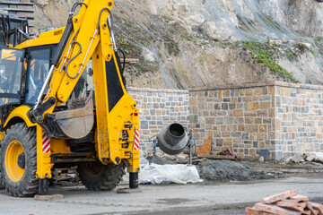 Work in progress: Yellow excavator and construction equipment against a background of masonry and...