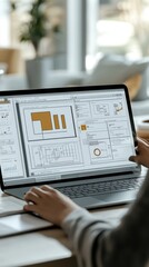 A person works on a laptop, designing wireframes and layouts for digital projects in a bright, modern office space