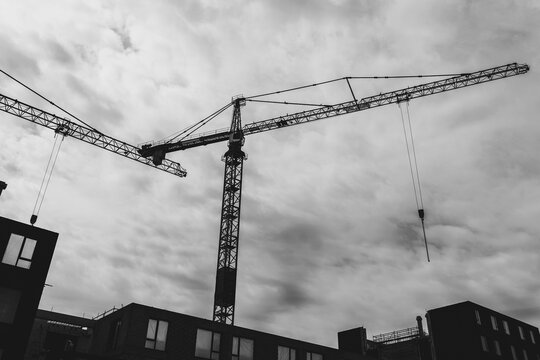 Monochrome image of construction crane silhouetted against a dramatic cloudy sky