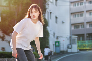 Beautiful young teenage girl skateboarding on the road in the city in sunny weather.