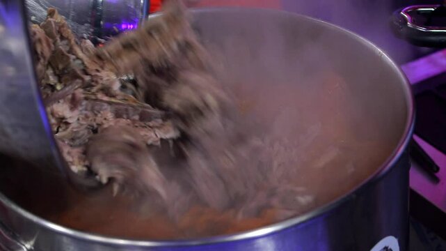 Pork backbones being added to a seasoning broth
