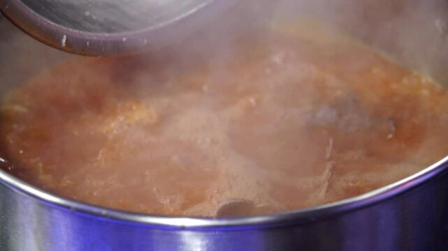 Pork backbones being added to a seasoning broth