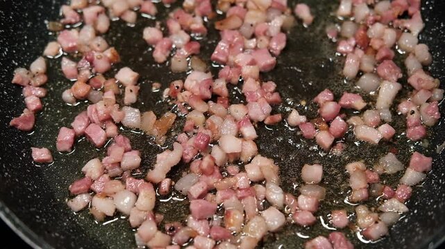 chef roasts cubes of bacon or Italian pork guanciale or pancetta in a pan for Italian pasta carbonara , A woman cooking Italian spaghetti carbonara pasta 