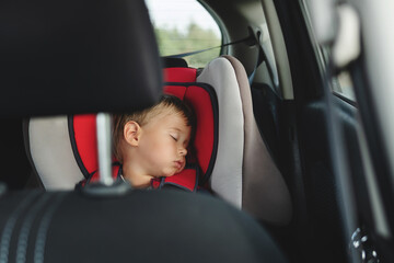 Adorable boy peacefully sleeping in  a car seat inside a vehicle