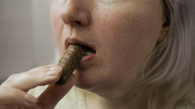 hungry chubby overweight woman eating chocolate bar, close-up of face