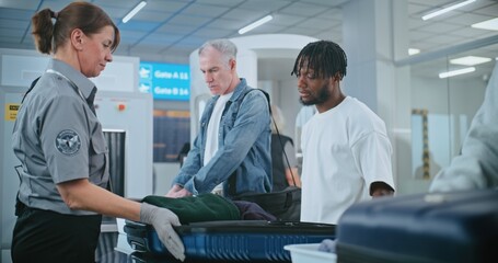 Security Checkpoint in Airport Terminal: Female TSA Worker Inspecting Baggage of Passenger before...