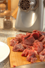Pieces of raw meat are prepared for scrolling in an electric meat grinder. Cooking. Close-up