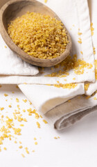 Raw dry uncooked yellow bulgur grain in a wooden bowl on white table cloesup. Ancient food