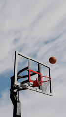 Naklejka premium Basketball in Motion Towards Hoop Against a Cloudy Sky, 3D rendered illustration