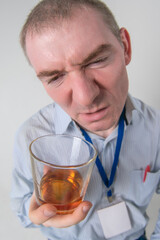 A drunk doctor looks at a glass of alcohol with a grimace of disgust. Close-up wide-angle shot