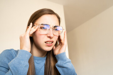 Woman with glasses looking at laptop screen squinting and touching her temples. Digital eye strain, eye fatigue, issues related to excessive gadget use, the impact of screens on vision, digital era.