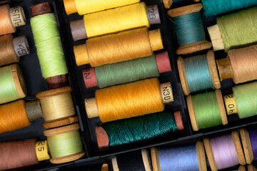 Lot of Colored spools with thread in dark plastic box close up
