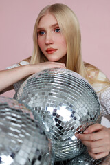 A festive party with disco balls. Studio fashion shoot with a blonde female model