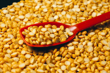 Closeup shot of Yellow chana dal and Organic Bengal Gram (Cicer arietinum) with a spoon.