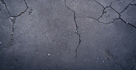 Obraz premium A close-up view of a cracked, weathered asphalt surface, showcasing various fissures and textures.