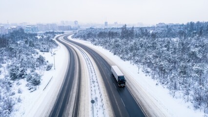 Obraz premium Aerial View of a Semi Truck Driving on a Snow-Covered Highway Surrounded by a Forest During Winter