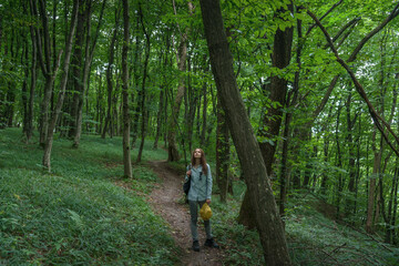 Obraz premium Smiling woman walking in lush forest during nature getaway