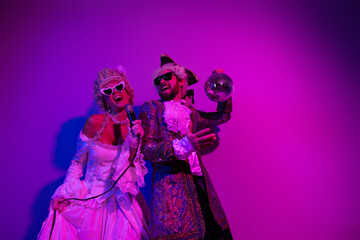 Fototapeta premium Two People in Vintage Costumes Dancing Under Neon Purple Light