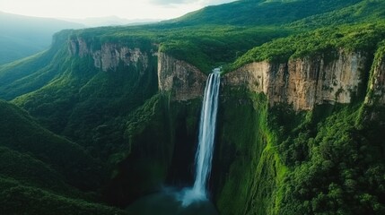 Obraz premium Majestic waterfall cascading down a lush green cliff in a serene natural landscape