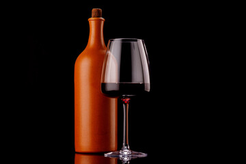Elegant presentation of red wine in a glass and a bottle against a dark background