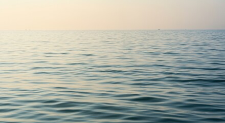 Obraz premium Serene ocean waves gently lapping against the shore during sunset, with a calm horizon