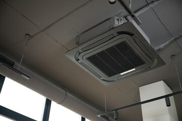 Ceiling mounted cassette air conditioner in modern building. Loft style. Industrial interior design.
