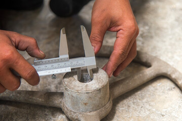 Close up scene the machine operator measuring inside dimension of cast iron parts by Vernier caliper.