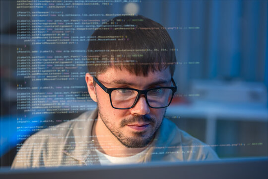 A young Caucasian programmer in eyeglasses intensely coding late at night. Experience the dedication of tech professionals driving digital transformation.