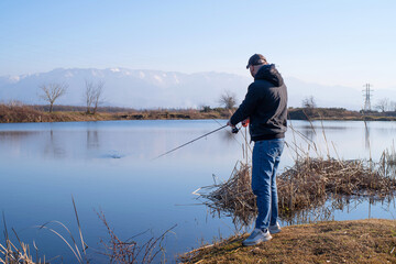 Fishing with a spinning rod. A man fisherman catches fish with a spinning rod on a lake against the...