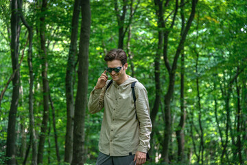 Front view portrait of a smiling man talking on a smartphone in a forest.