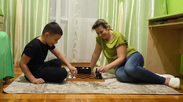 Mother and son playing chess at home. Leisure and board games.