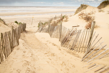 Sandy path with wooden fences to large empty beach and sea, Formby, England,UK