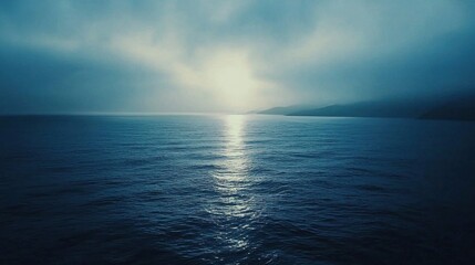 Obraz premium Blue ocean waters reflecting sunlight through a cloudy atmosphere horizon