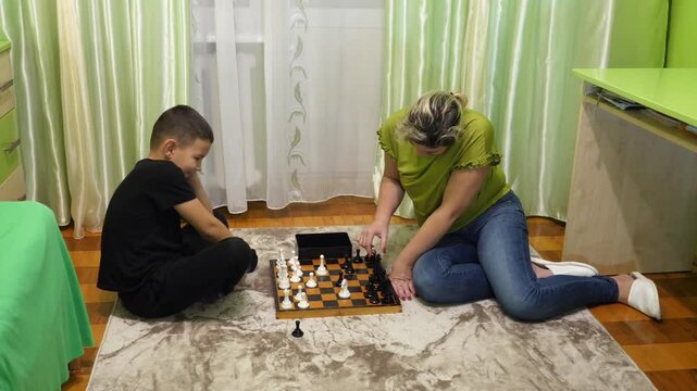 Mother and son playing chess at home. Leisure and board games.