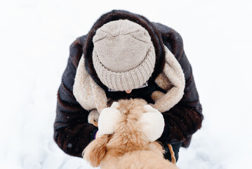 young woman hugging her dog, red poodle standing on white snow in winter day, dogwalking concept,...