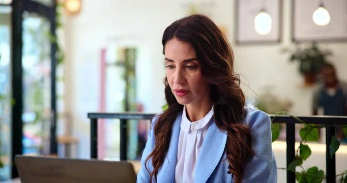 Business, documents and laptop with woman in coffee shop for editing or publishing. Computer, online magazine and paper with mature editor at in cafe or restaurant for proofreading article or report