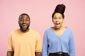 Surprised african american couple gasping and showing amazement on pink background