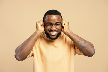 Young man covering his ears ignoring loud noise or music