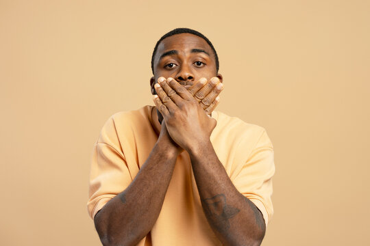 Young man covering his mouth with his hands