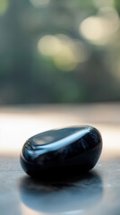 Close-up of obsidian,  exuding a glossy black sheen. Its smooth surface absorbs light, reflecting subtle glimmer