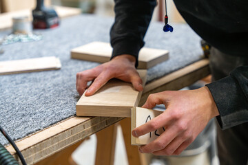Focus sur la fabrication de meubles en bois dans un atelier de menuiserie, créés sur mesure pour un hôtel haut de gamme, mettant en valeur le savoir-faire artisanal et les matériaux de qualité.