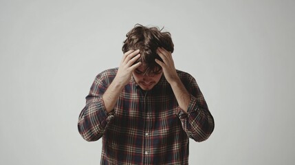 Man in checkered shirt shows signs of stress indoors