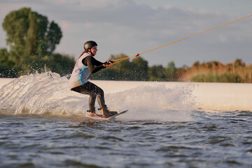 A wakeboarder girl deftly maneuvers on the lake, creating dynamic splashes against the background...