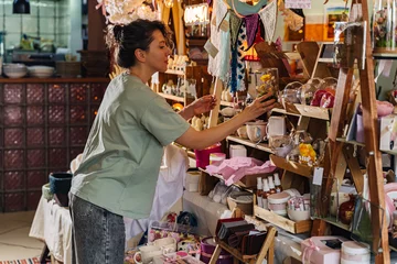 Artisan organizing handcrafted decor at a market stall. Variety of handmade crafts and decorations at local fair. © igishevamaria