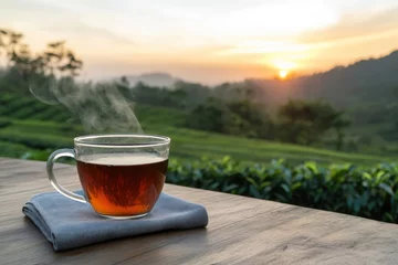 Fototapeten Steaming cup of tea enjoying sunrise over tea plantation © Miroslav